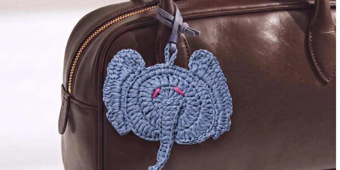 an elephant raffia charm on a brown leather bag