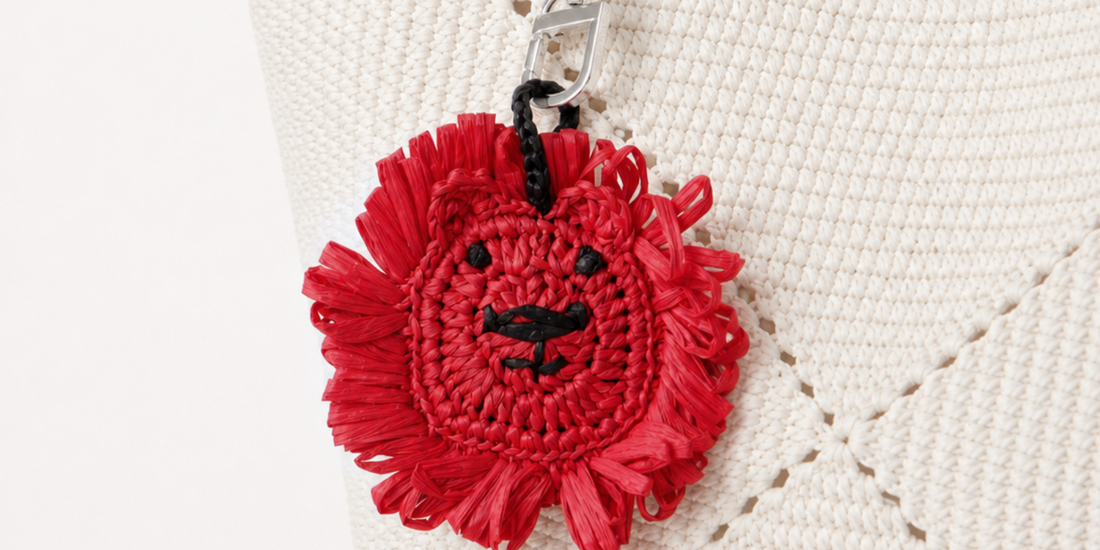A red raffia lion charm on a white woven bag