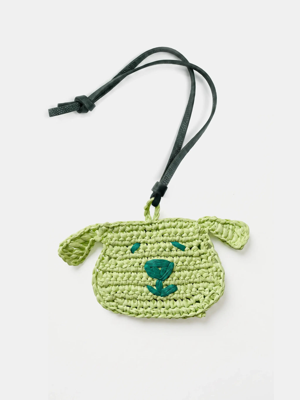 A light green woven dog charm with a dark green strap and a dark green embroidered face, shown on a plain white background.
