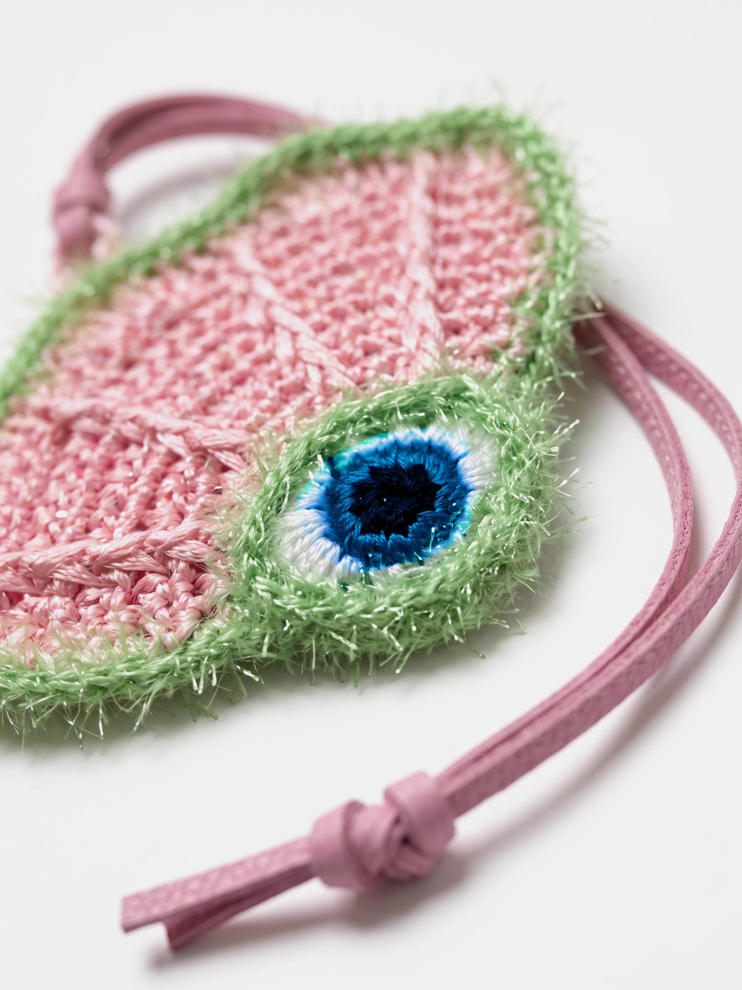 A close-up of a woven or knitted pink scallop bag charm