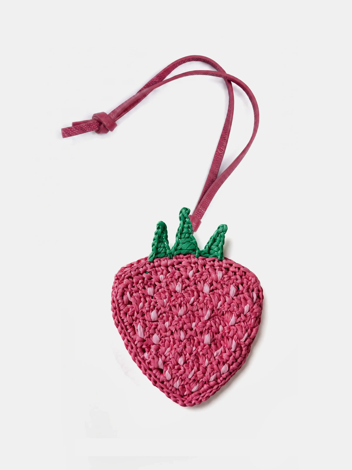 A pink crocheted strawberry bag charm with green leaf accents and a matching pink strap