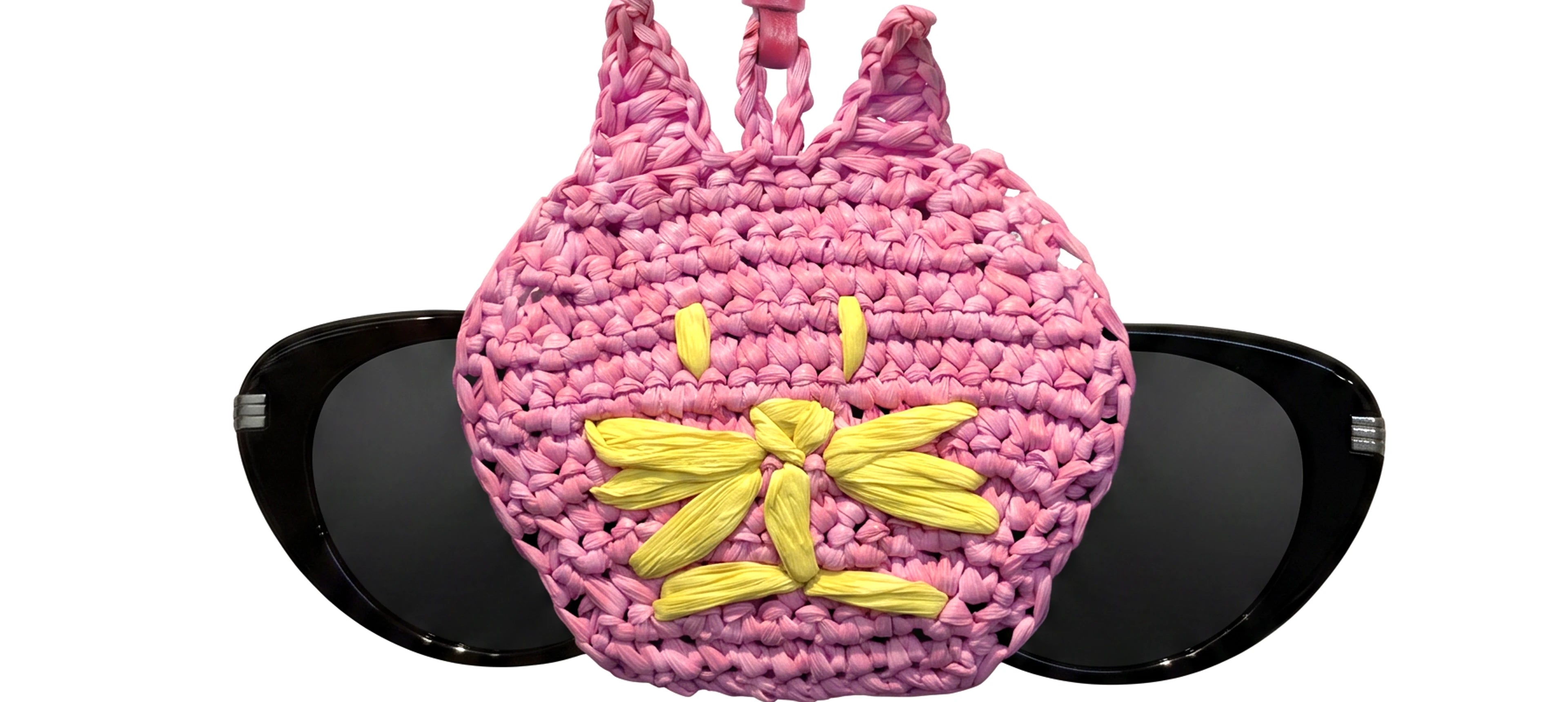 a pink cat head bag charm holding a pair of glasses