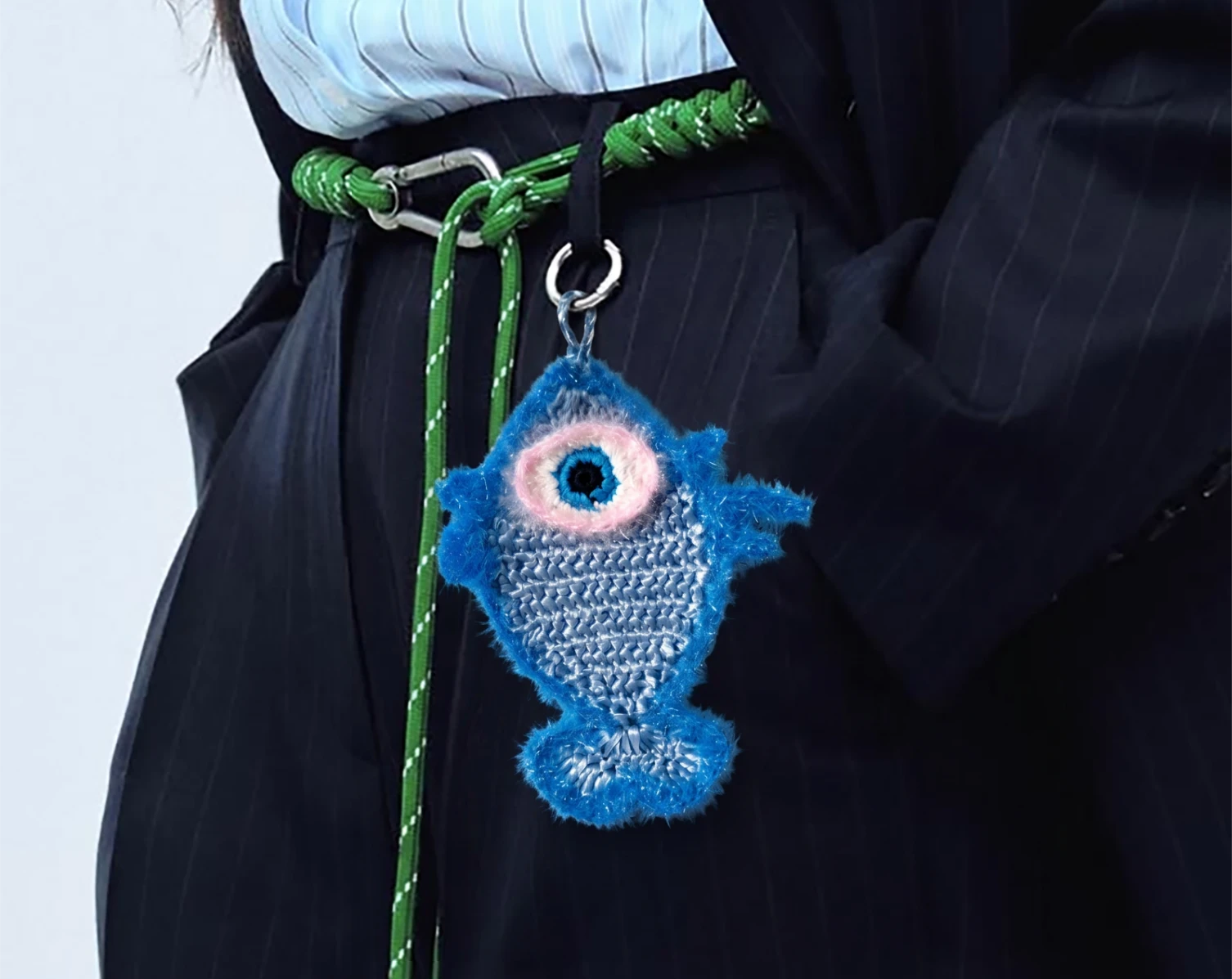 A close-up of a person wearing a dark pinstripe jacket and skirt, with a bright blue fish charm