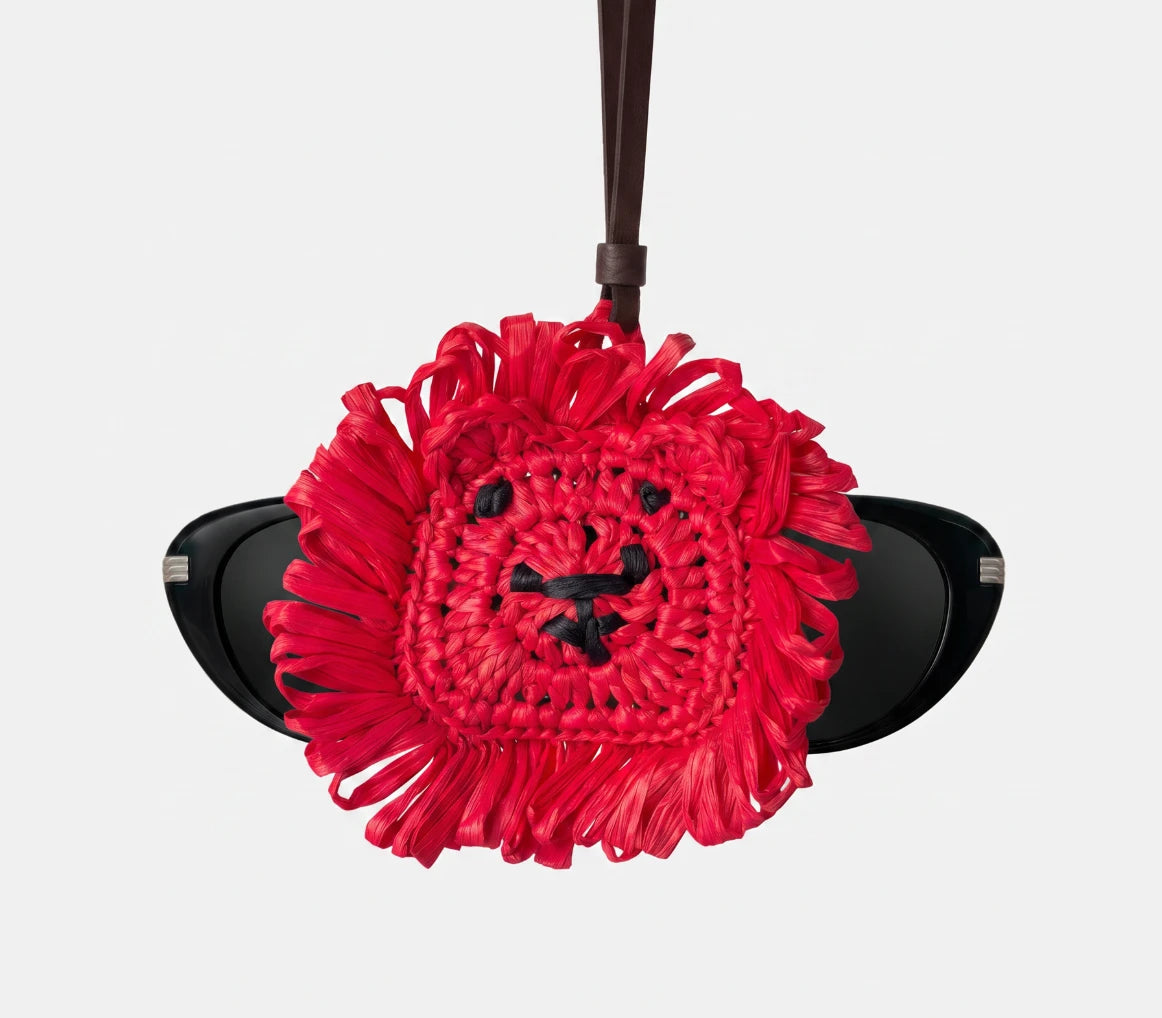 A bright red raffia lion charm with a pair of glasses going through